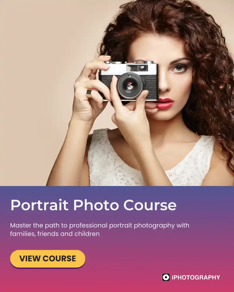 a woman with brown frizzy hair holding a camera looking at us