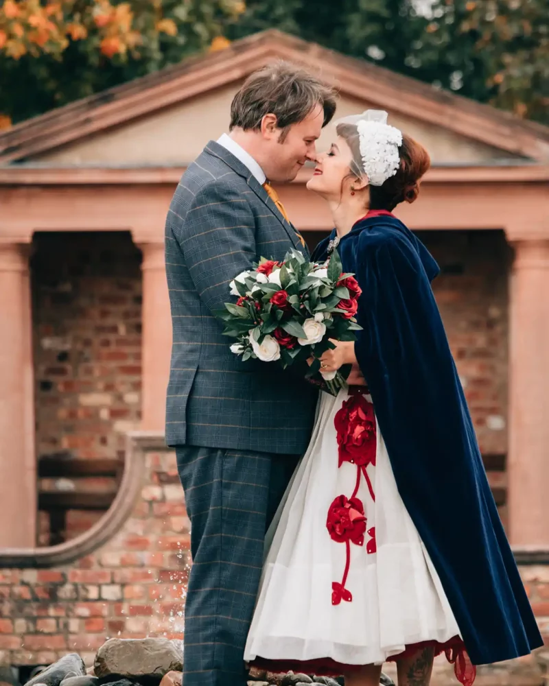 A bride and groom touching noses in front of a water fountain